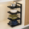 Black 4-tier adjustable metal pot rack with pans and cookers placed on countertop next to wooden cabinets